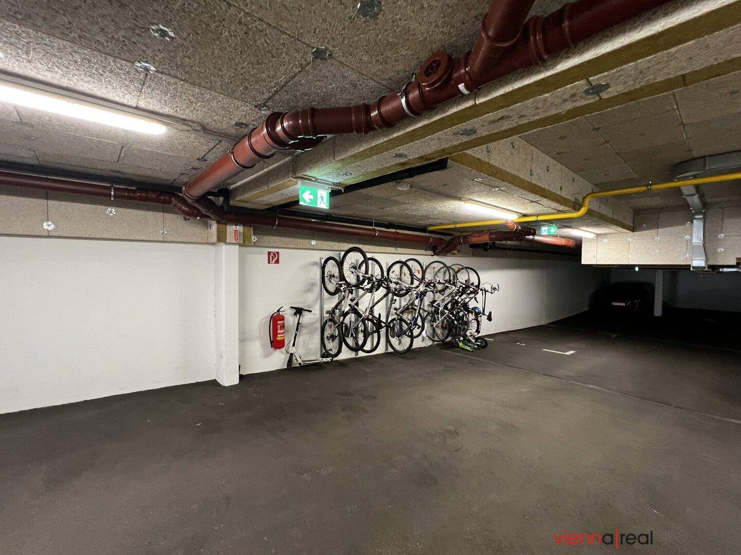 Fahrradabstellraum im Untergeschoss mit Wandhalterungen für mehrere Fahrräder und Brandschutz.