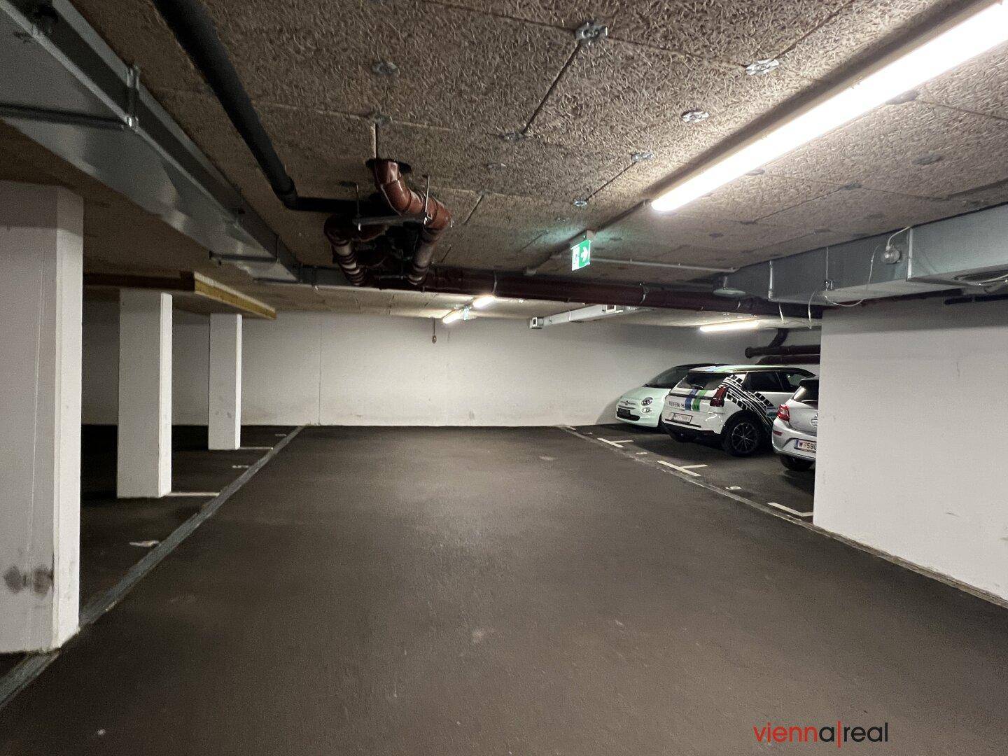 Geräumige Tiefgarage mit weiteren Stellplätzen und Säulen, die die Decke stützen.