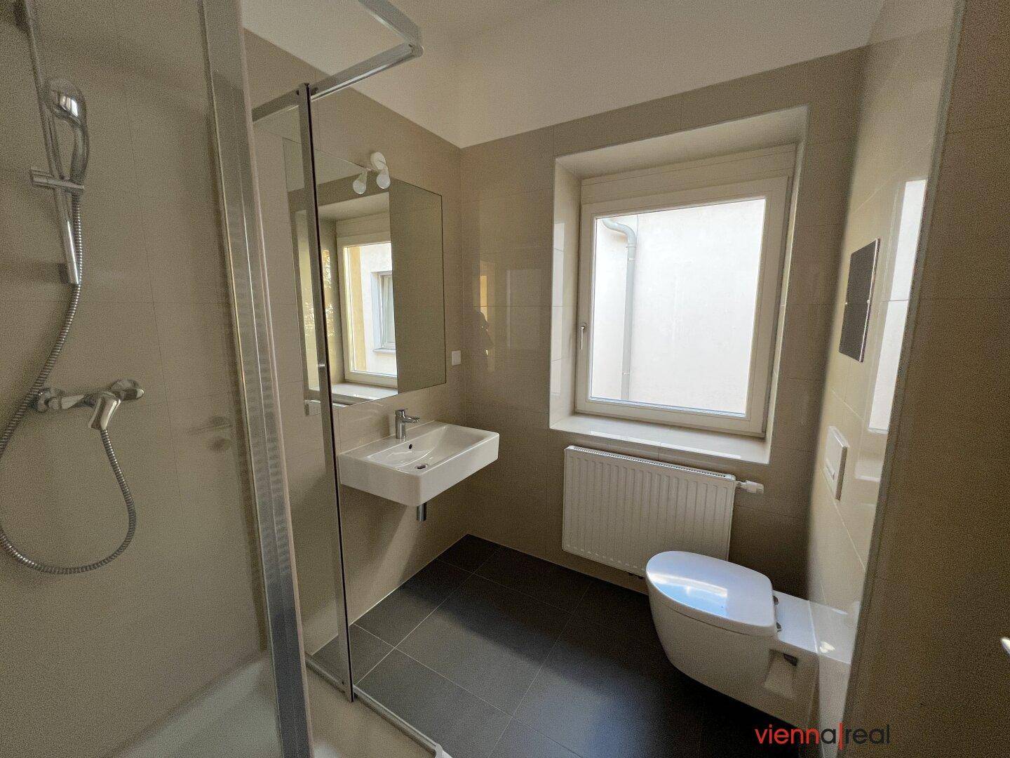 Modernes Badezimmer mit Duschkabine, Waschbecken, WC und Fenster für Tageslicht.