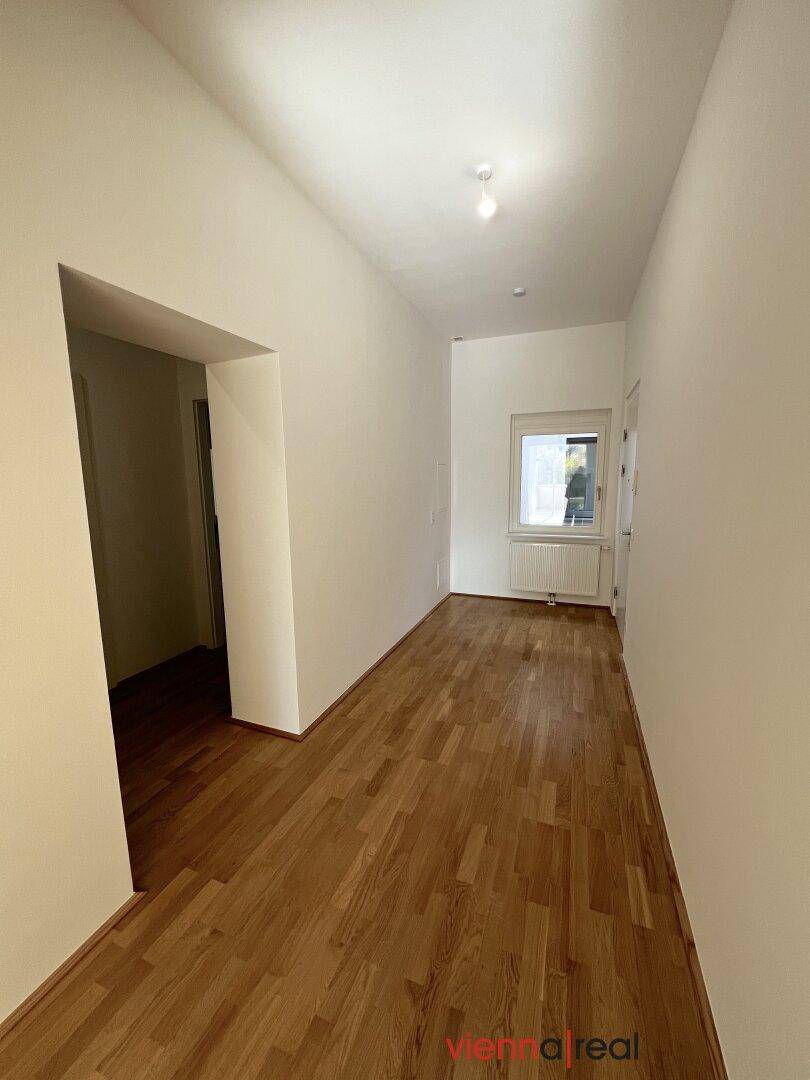 Geräumiger Flur mit Parkettboden und weiß gestrichenen Wänden, verbindet die Räume.