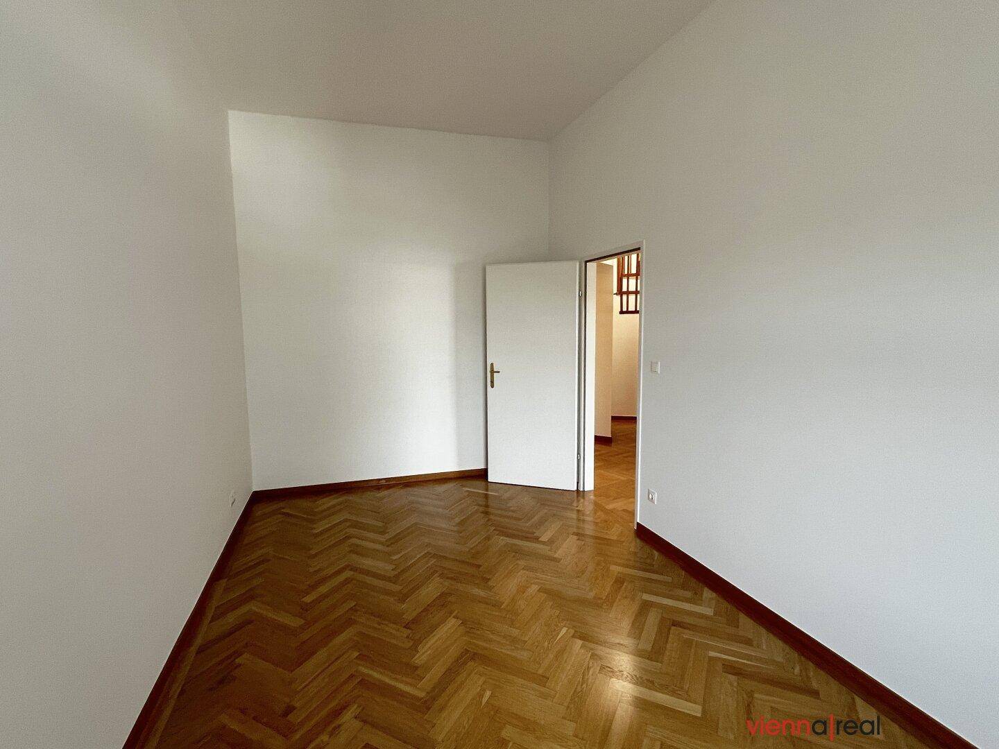 Kleinerer Raum mit Fischgrätparkett und weißen Wänden, ideal als Schlaf- oder Arbeitszimmer.