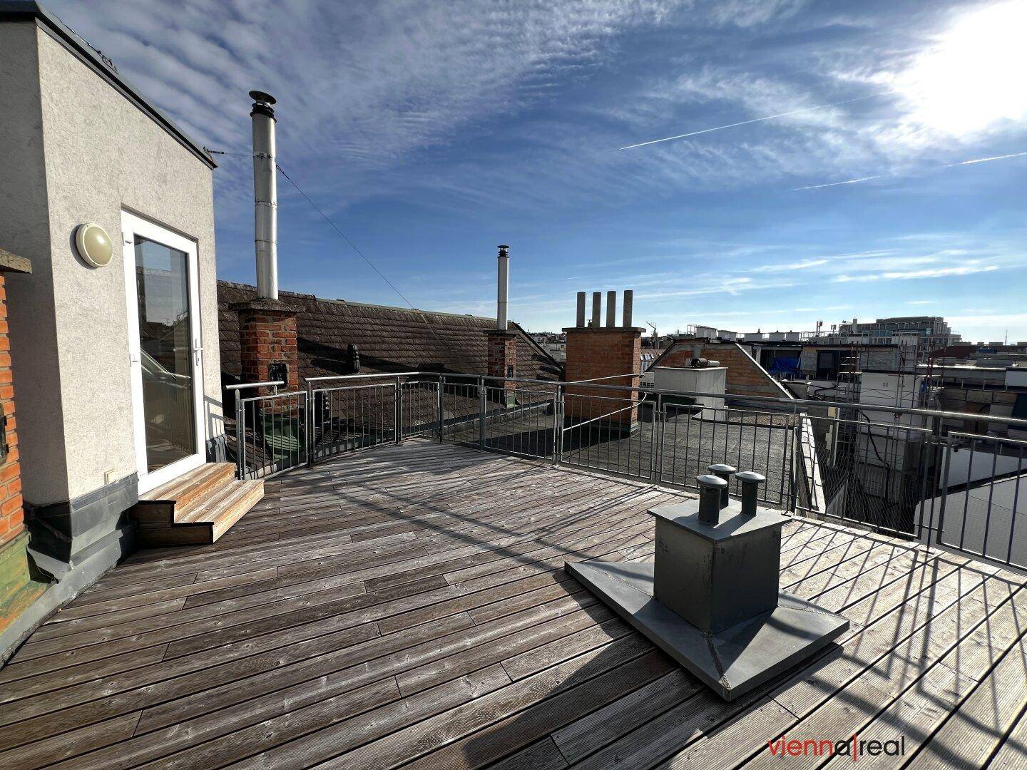 Sonnige Dachterrasse mit Holzboden und Panoramablick über die Stadtlandschaft.