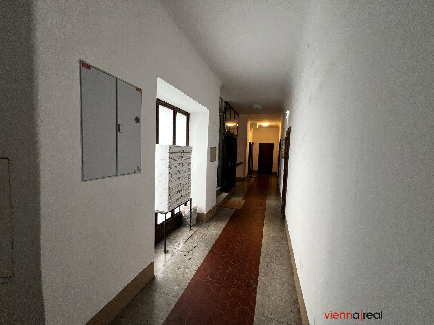Heller Flur im Erdgeschoss eines Altbaus mit Briefkästen und Zugang zum Aufzug.