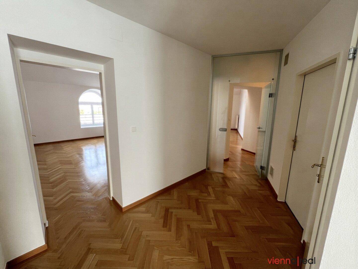 Heller Flur mit Fischgrätparkett und Türen zu verschiedenen Räumen.
