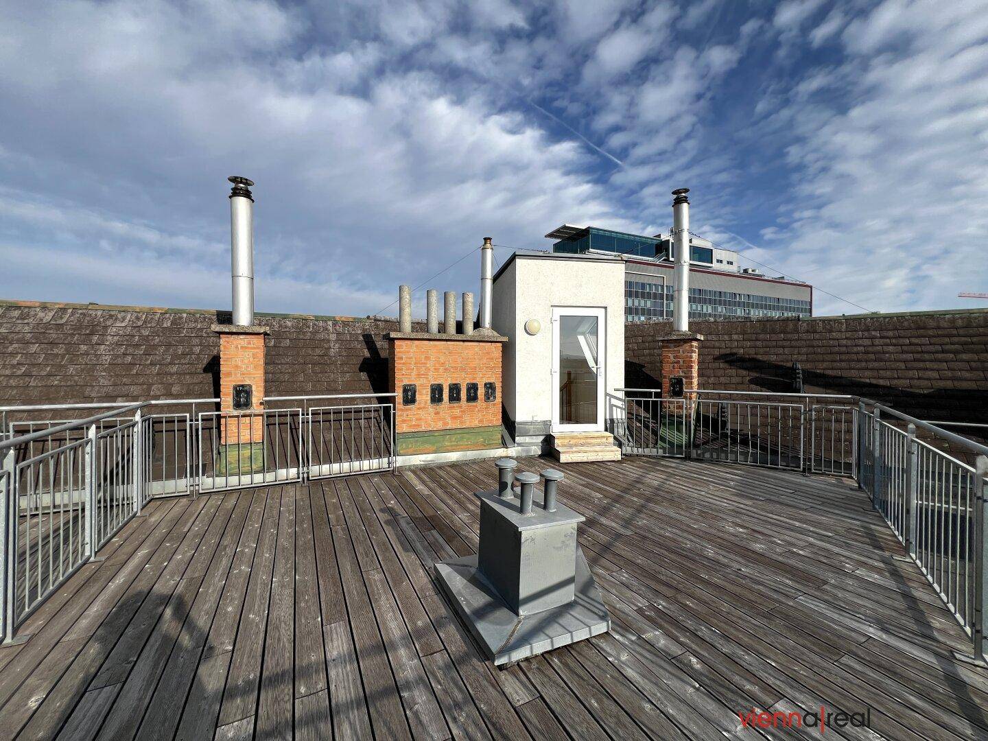 Geräumige Dachterrasse mit Holzboden und weitem Blick über die Stadt.