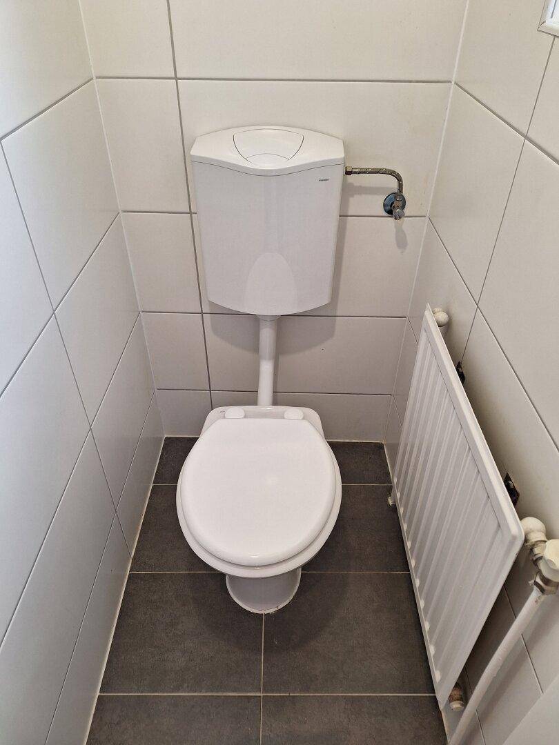 Kleines Gäste-WC mit Toilette und dunklen Bodenfliesen.