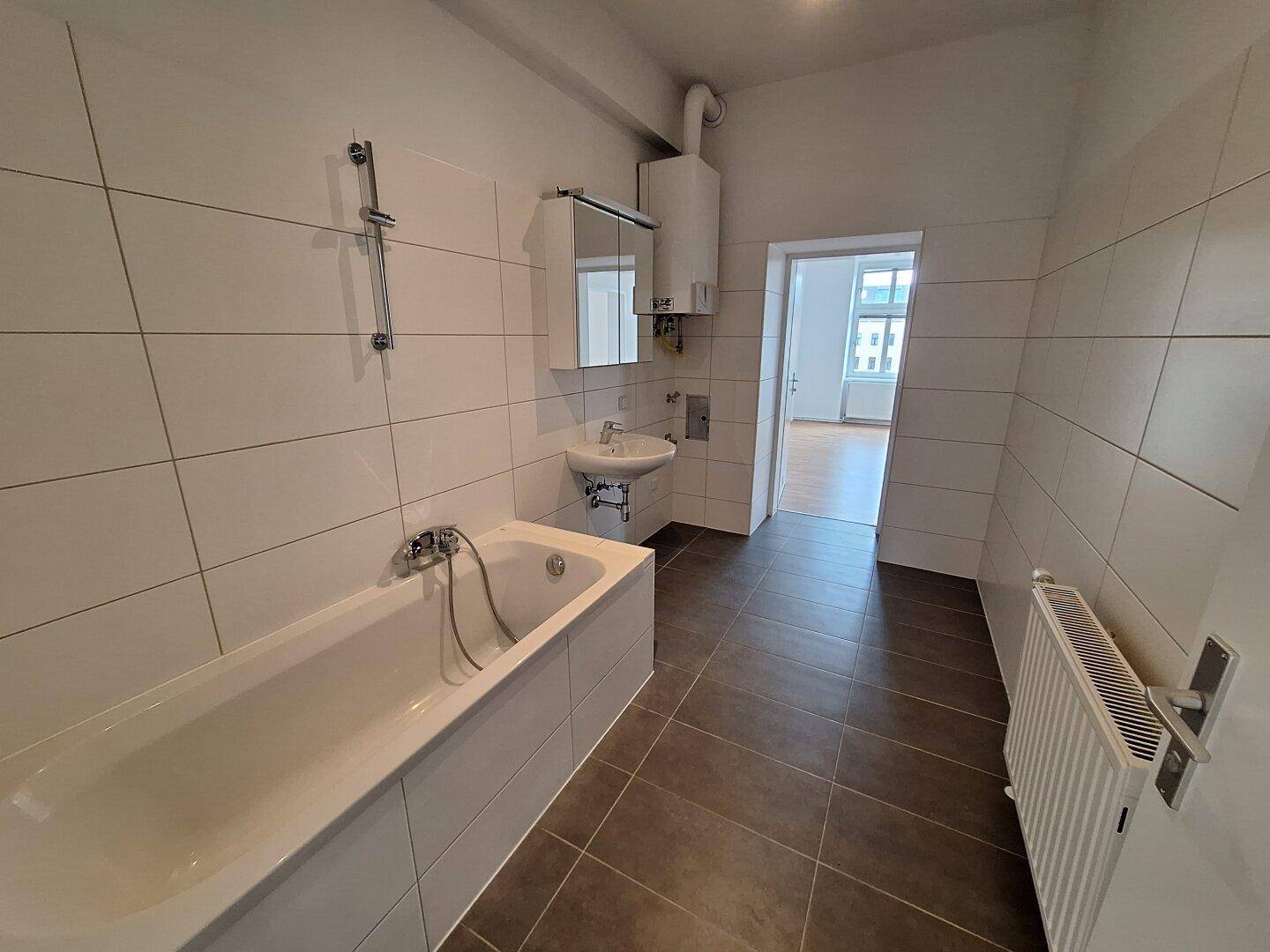 Modernes Badezimmer mit Badewanne, Waschbecken und weißen Wandfliesen.