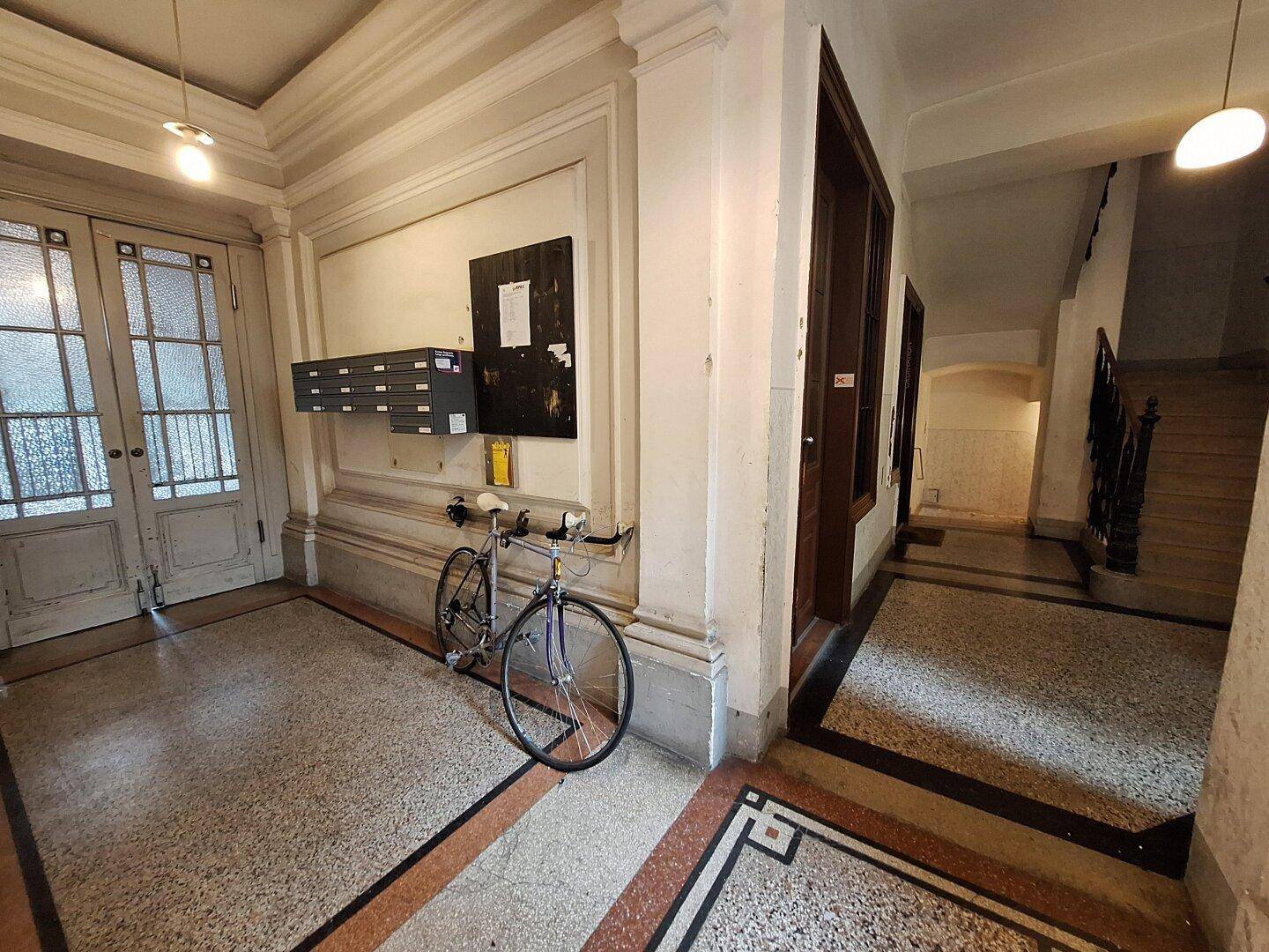 Eingangsbereich eines Altbaus mit Terrazzoboden und Fahrradabstellmöglichkeit.