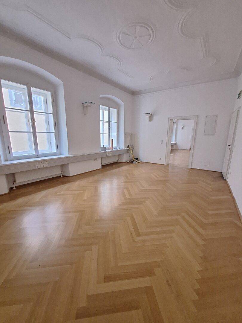 Großzügiges Zimmer mit kunstvollem Stuck an der hohen Decke und klassischem Fischgrätparkettboden.