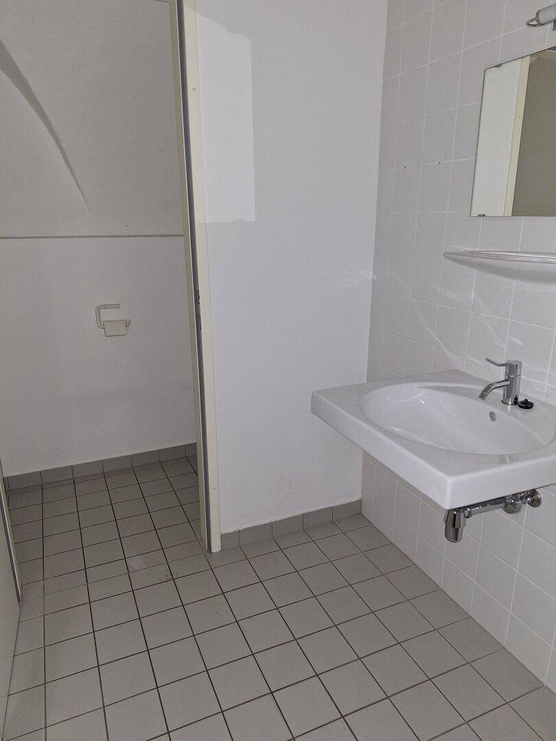 Helles Badezimmer mit modernem Waschbecken und weiß gefliesten Wänden und Boden.