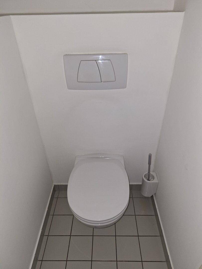 Sauberer Toilettenraum mit wandhängendem WC und gefliestem Boden, minimalistisch gestaltet.