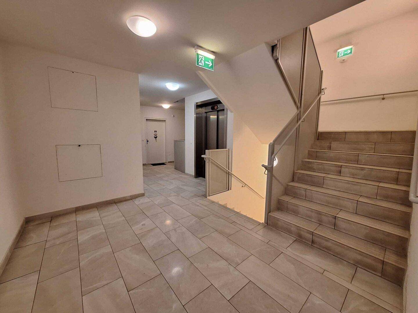 Treppenhaus und Aufzug im Gemeinschaftsbereich des Gebäudes mit Fliesenboden.
