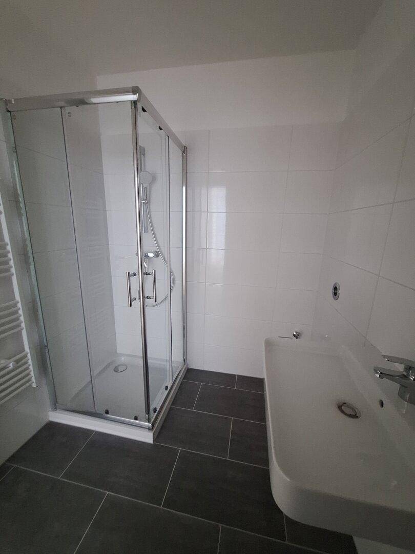 Modernes Badezimmer mit Duschkabine, Waschbecken und weißen Wandfliesen.