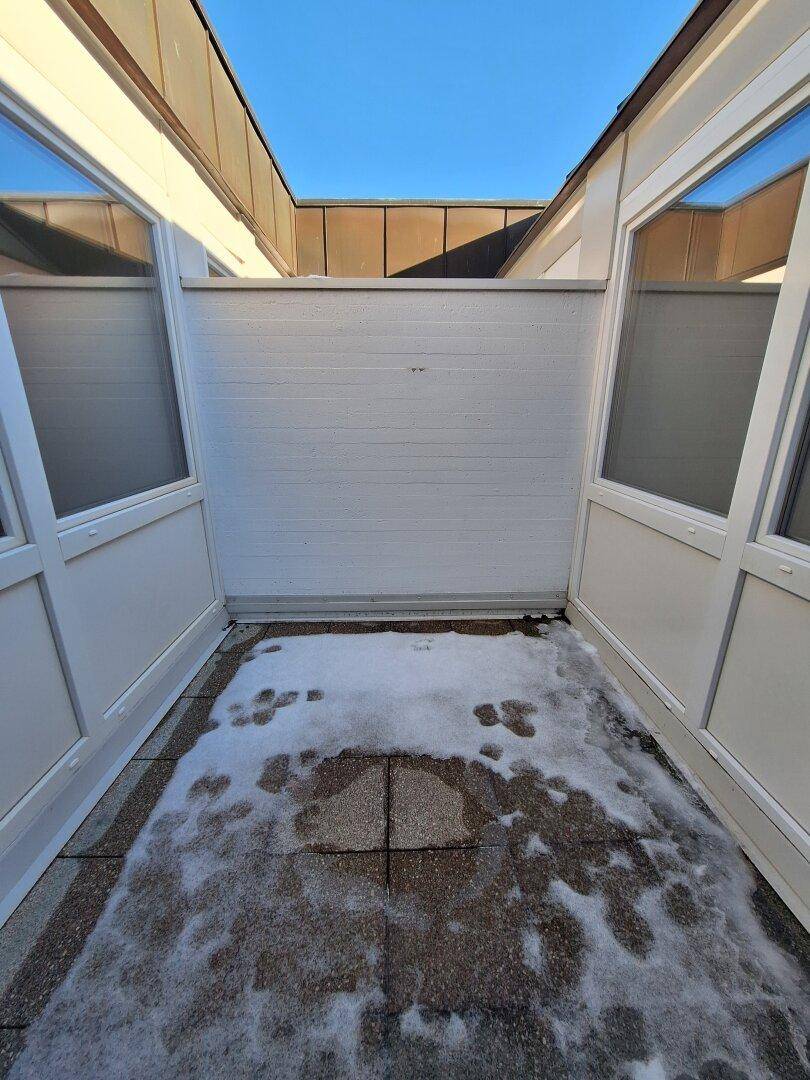 Verglaste Loggia mit Fliesenboden und Blick auf den Himmel, bedeckt mit Schnee.