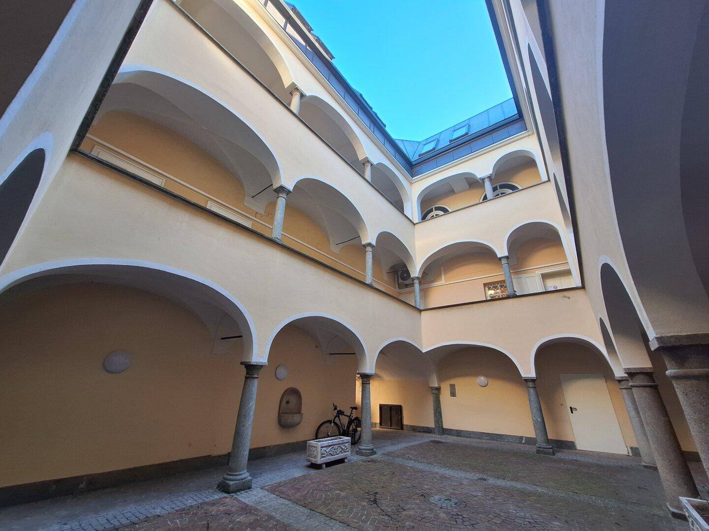 Historischer Innenhof mit Arkaden, Säulen und einem gepflasterten Boden.