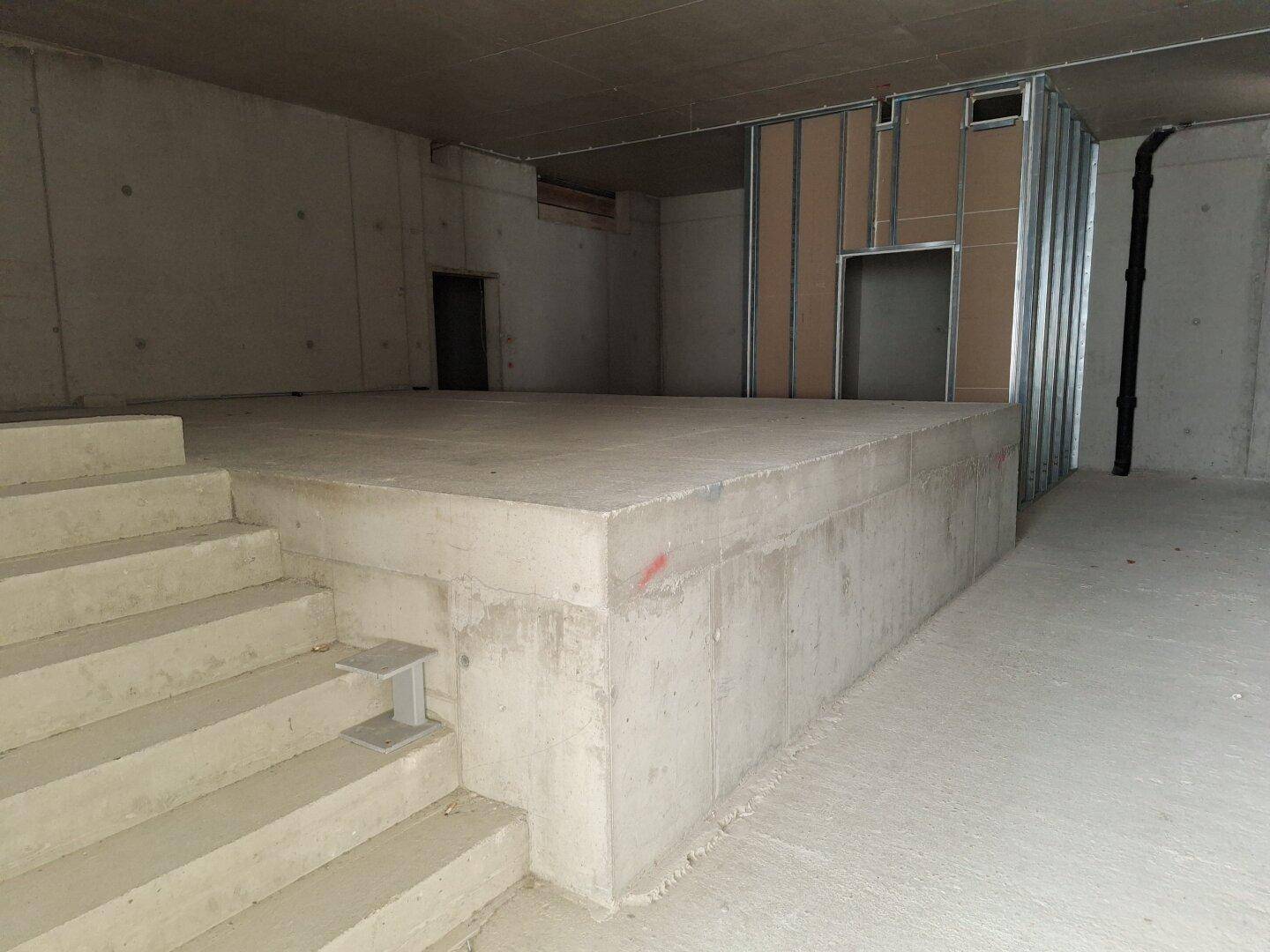 Rohbau mit erhöhter Betonplattform und Betontreppe, Metallständerwerk für Trockenbau ist sichtbar.