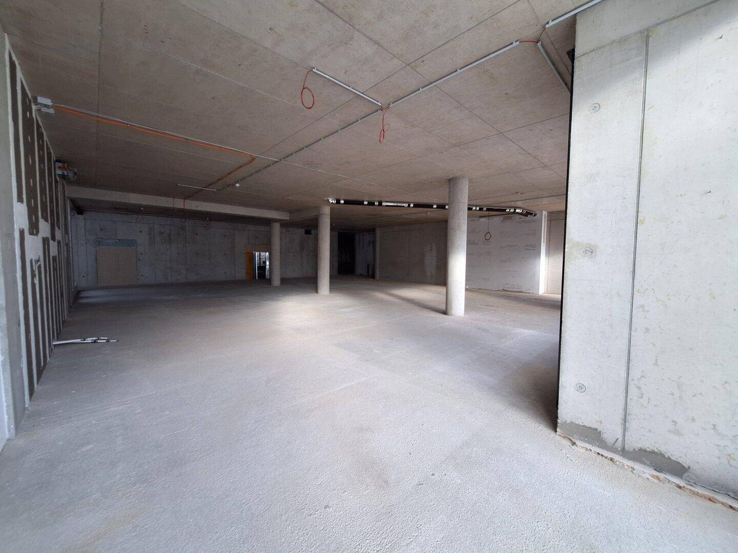 Großer, offener Rohbau mit Betonsäulen und weiten Fensterfronten, bietet vielseitige Gestaltungsmöglichkeiten.