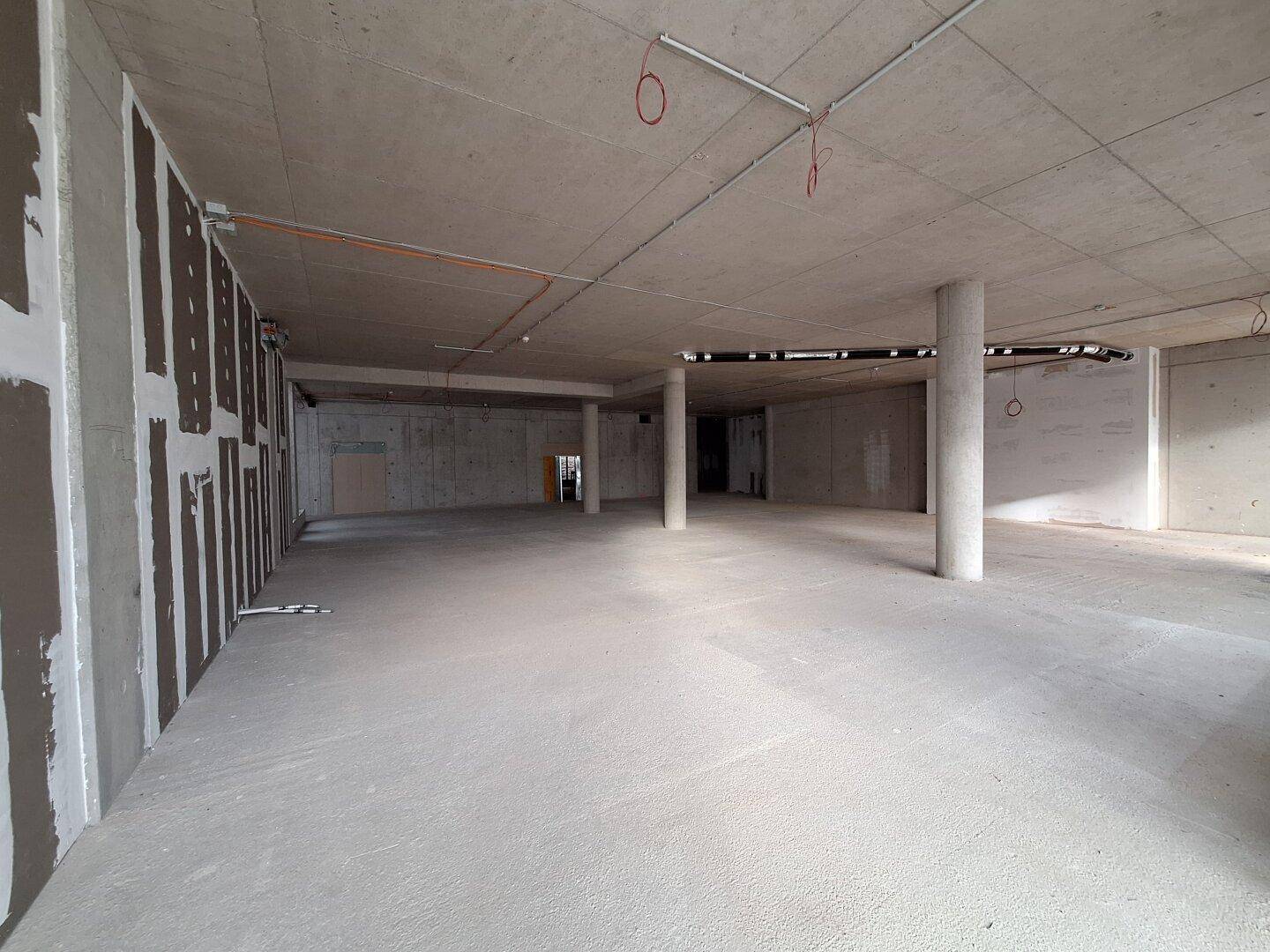 Großer, offener Rohbau mit Betonsäulen und weiten Fensterfronten, bietet vielseitige Gestaltungsmöglichkeiten.