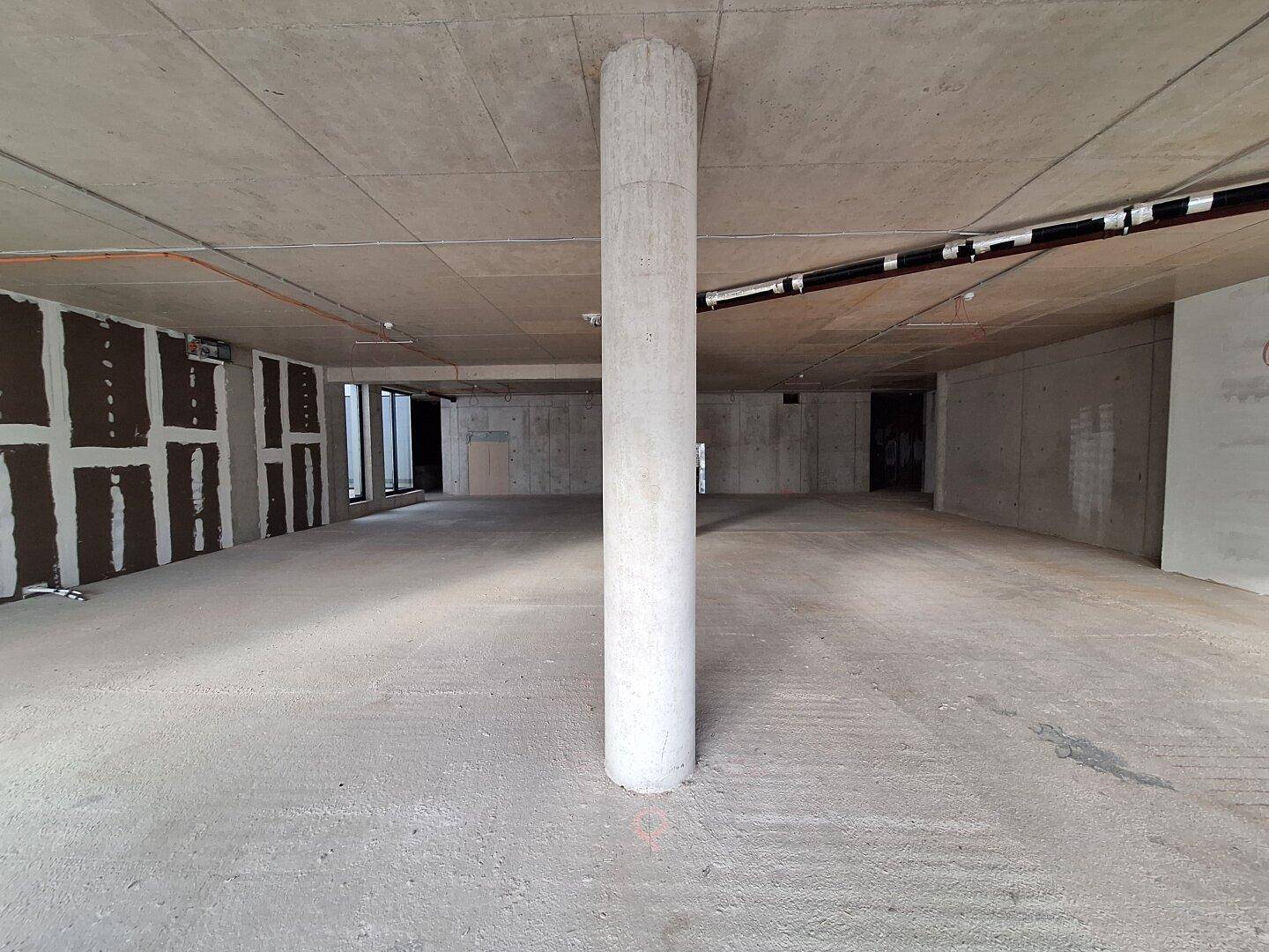 Unfertiger Innenraum mit einer zentralen Betonsäule, Betonboden und -wänden, bereit für den weiteren Ausbau.