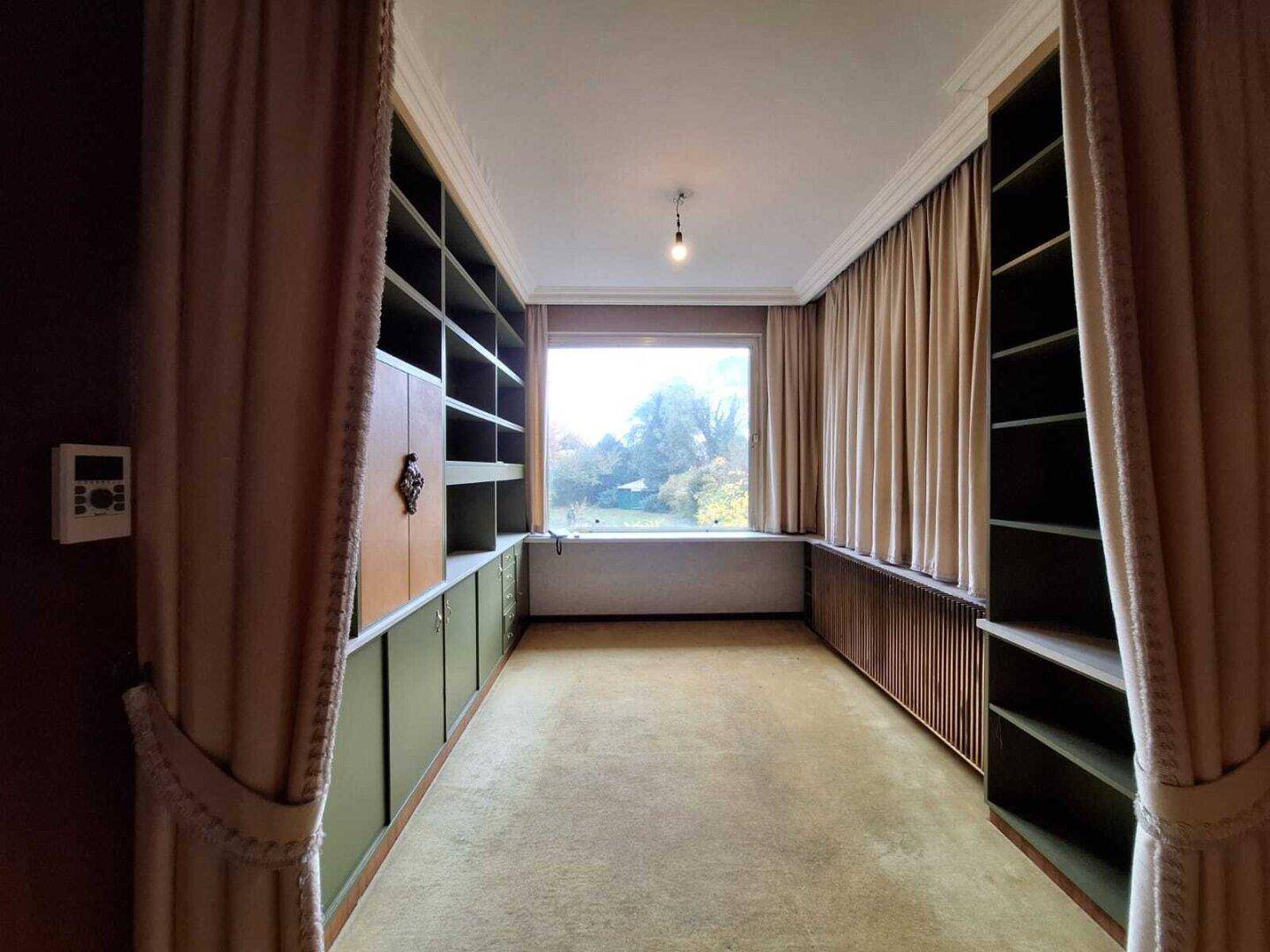 Arbeitszimmer mit eingebauten Bücherregalen, Teppichboden und Blick ins Grüne.