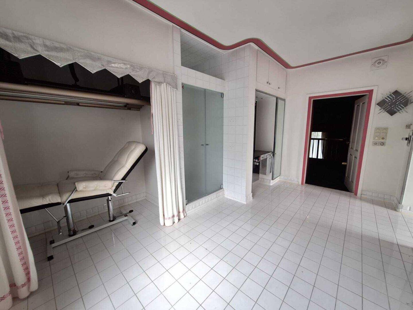 Großes Badezimmer mit Duschkabine und einem Behandlungsstuhl, ideal für Wellness-Anwendungen.