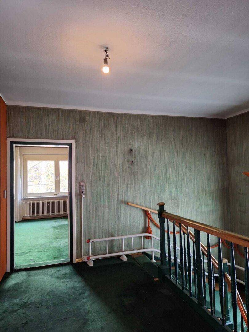 Obergeschoss-Flur mit grünem Teppichboden und Zugang zu mehreren Zimmern, im Vintage-Stil.