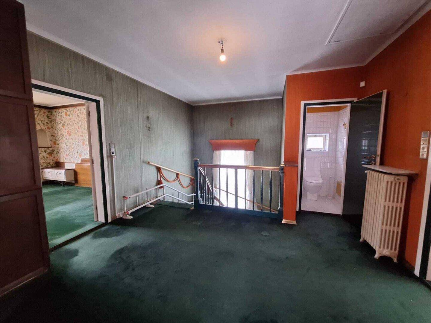 Obergeschoss-Flur mit grünem Teppichboden und Zugang zu mehreren Zimmern, im Vintage-Stil.