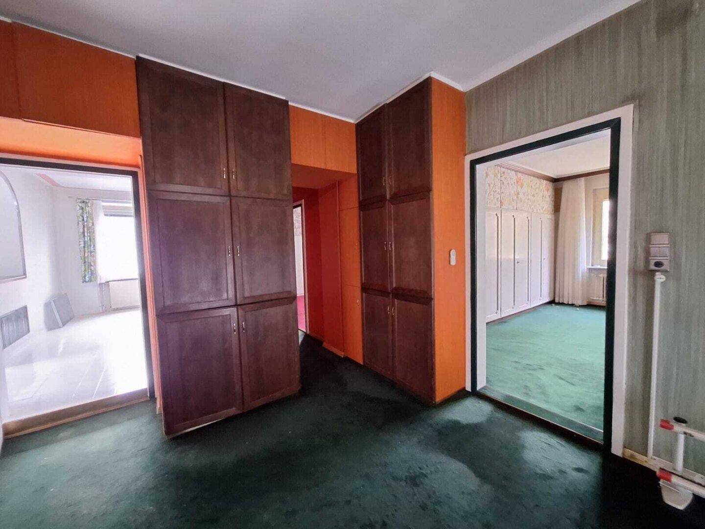 Obergeschoss-Flur mit grünem Teppichboden und Einbauschränken, im Vintage-Stil.