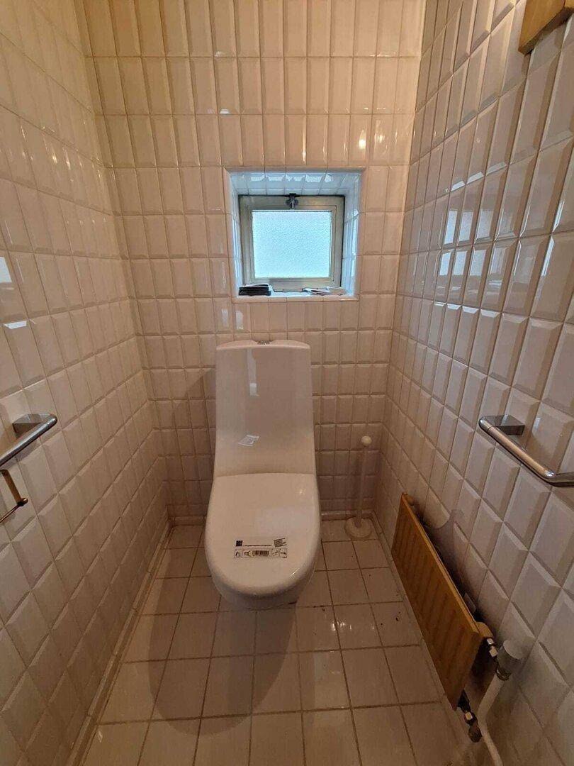 Kleines Gäste-WC mit weißen Fliesen, Fenster und Haltegriffen für Barrierefreiheit.