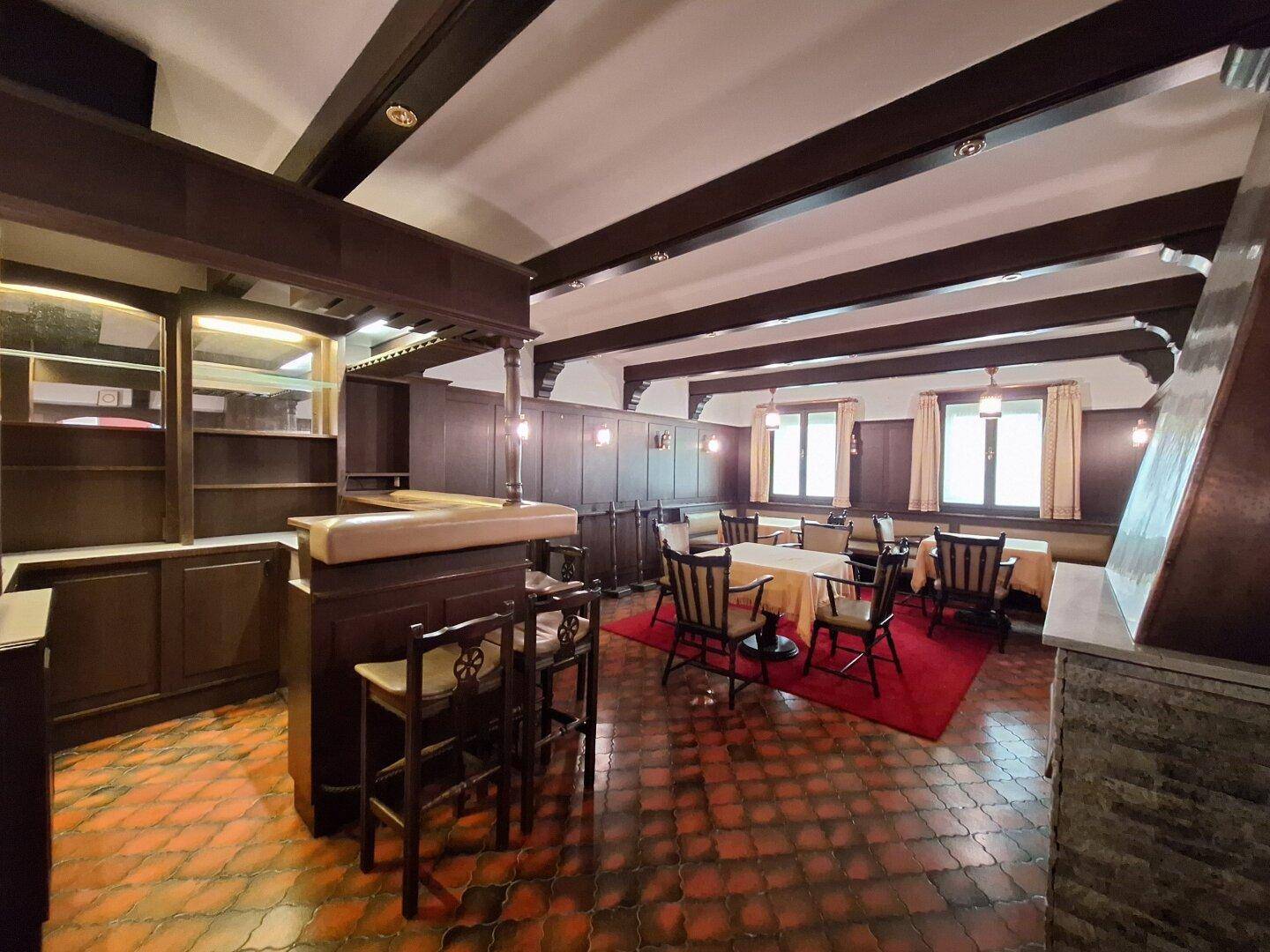 Rustikaler Essbereich mit Holzbalken, Bar und traditionellen Möbeln, ideal für Geselligkeit.