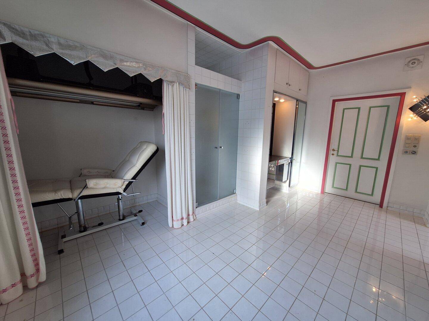 Großes Badezimmer mit Duschkabine und einem Behandlungsstuhl, ideal für Wellness-Anwendungen.