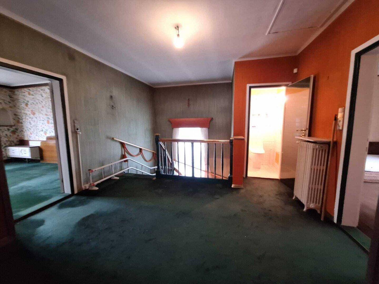 Obergeschoss-Flur mit grünem Teppichboden und Zugang zu mehreren Zimmern, im Vintage-Stil.