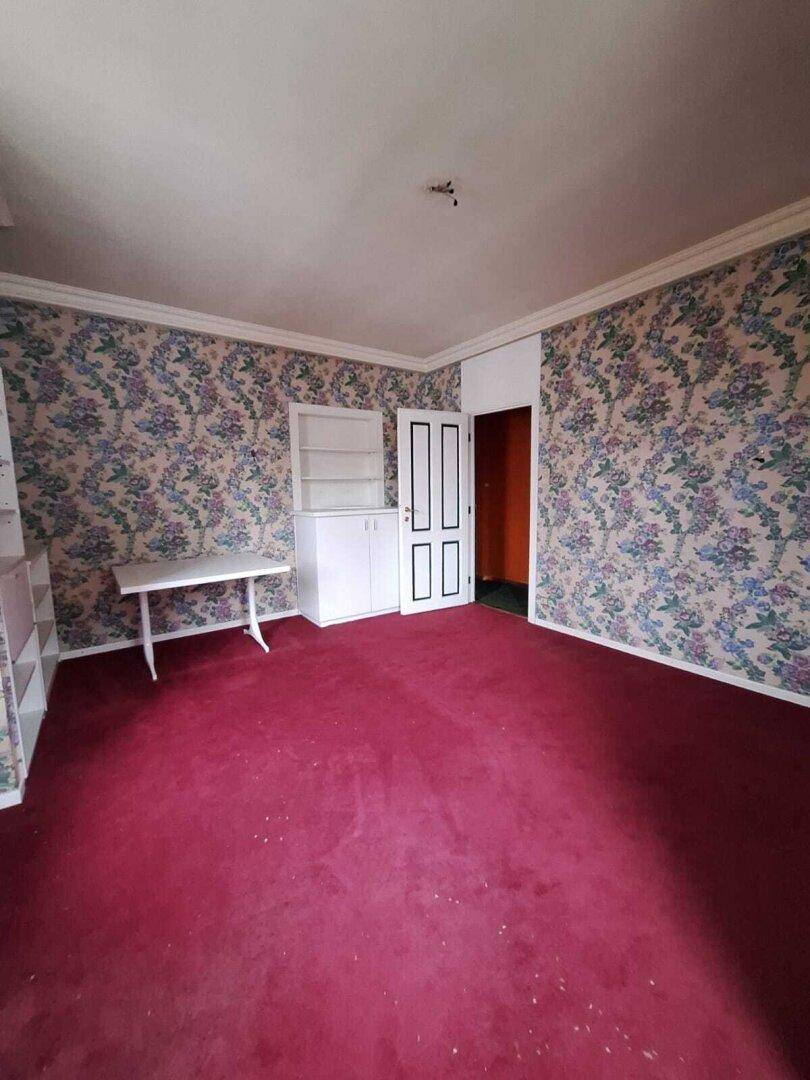 Schlafzimmer mit floraler Tapete, rotem Teppichboden und weißen Einbauschränken, im Vintage-Stil.