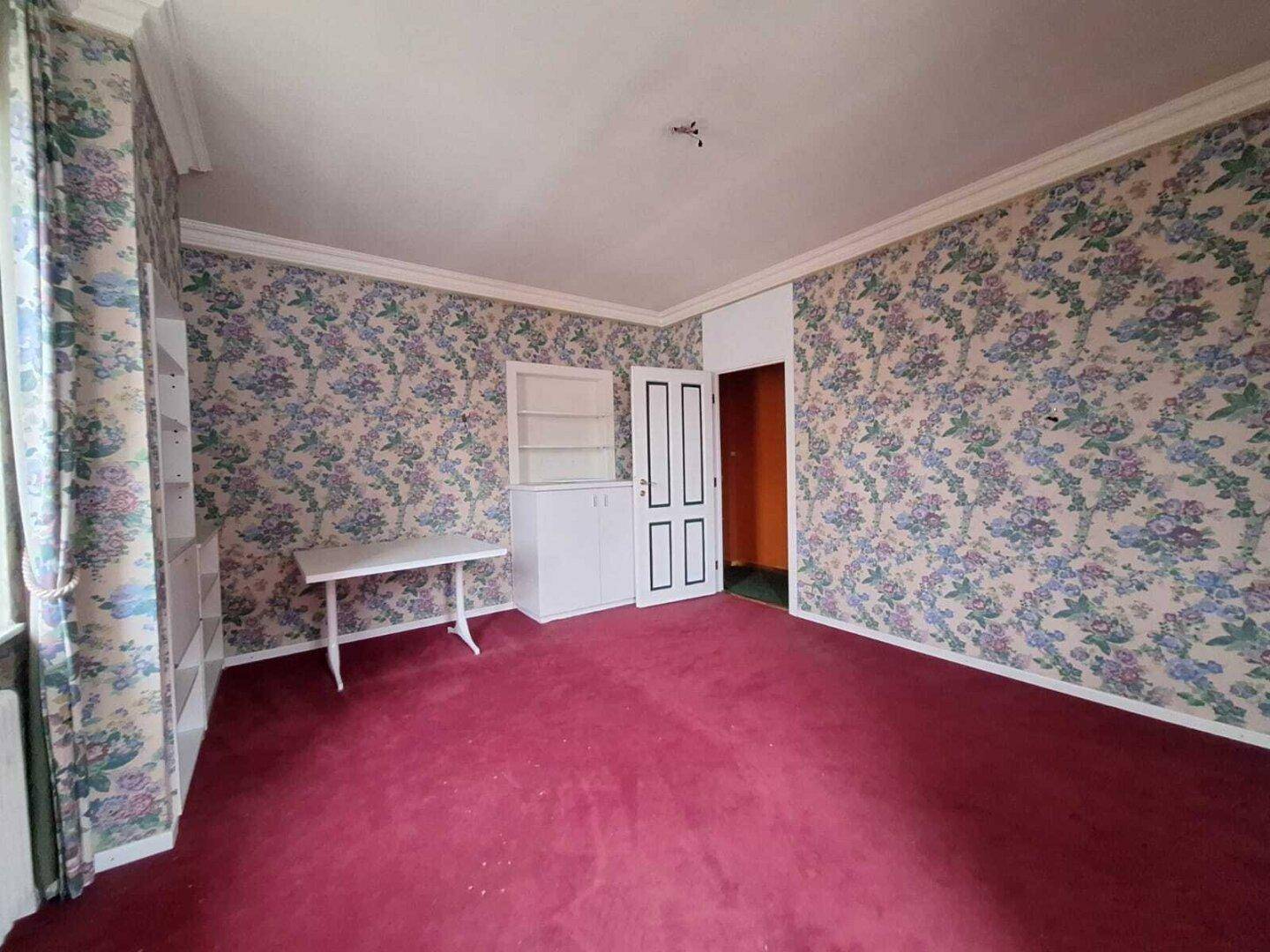 Schlafzimmer mit floraler Tapete, rotem Teppichboden und weißen Einbauschränken, im Vintage-Stil.