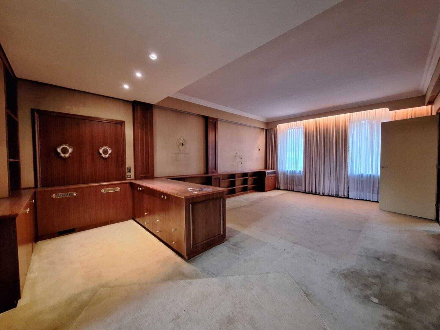 Geräumiges Büro mit umfangreichen Einbauschränken und Teppichboden in hellem Beige.