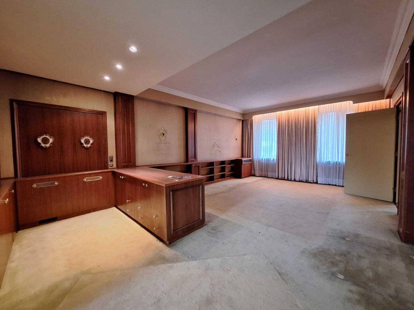 Geräumiges Büro mit umfangreichen Einbauschränken und Teppichboden in hellem Beige.