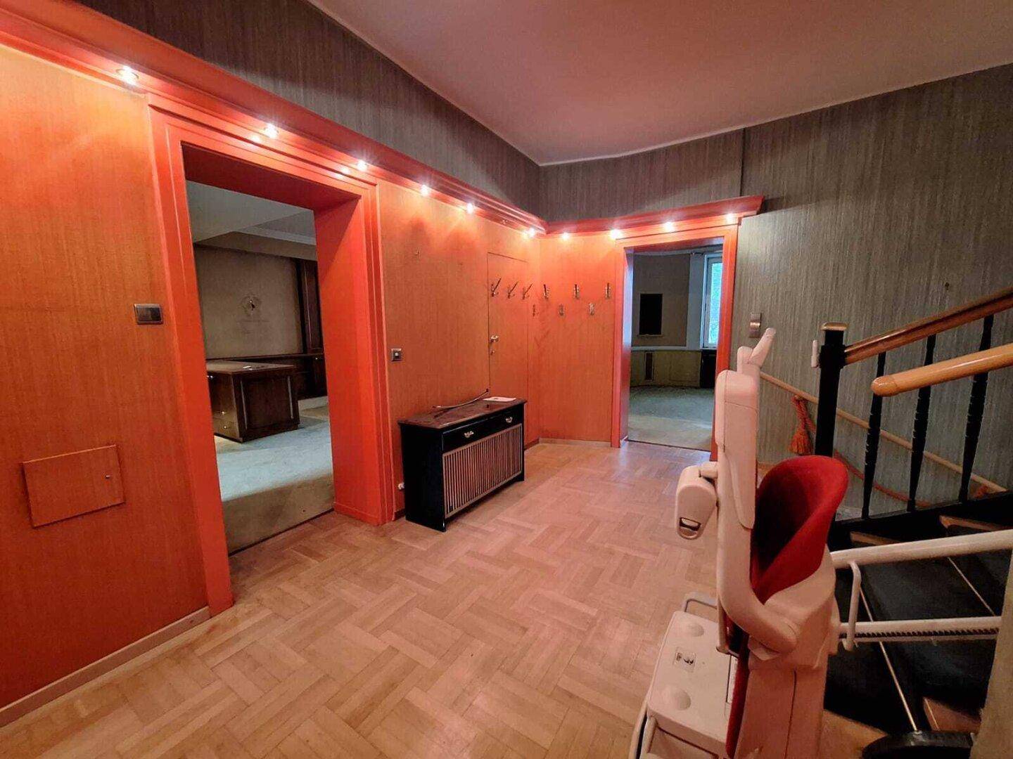 Eingangsbereich mit Holzparkett, Treppe und einem Treppenlift für verbesserte Barrierefreiheit.