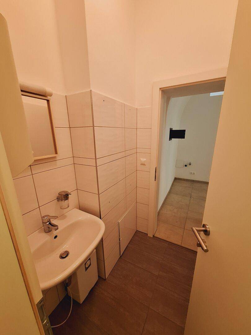 Toilettenbereich mit WC und hellen Wandfliesen, die eine saubere und funktionale Umgebung bieten.