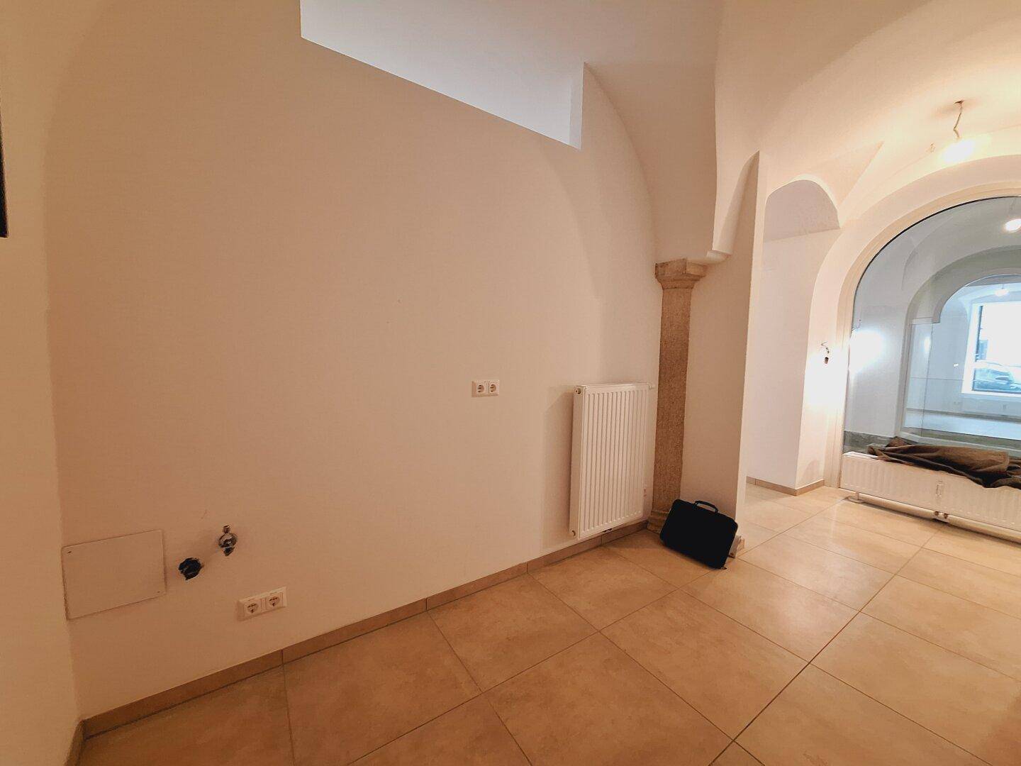 Kleiner Hauswirtschaftsraum mit Fliesenboden, Heizkörper und sichtbaren Anschlüssen an der Wand.