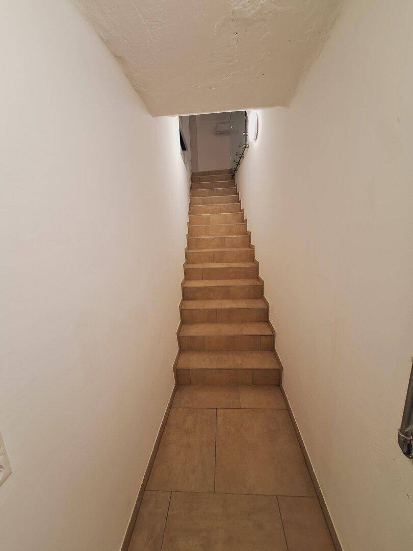 Lange Treppe mit Fliesenstufen, die in ein Untergeschoss oder einen Kellerbereich führt.