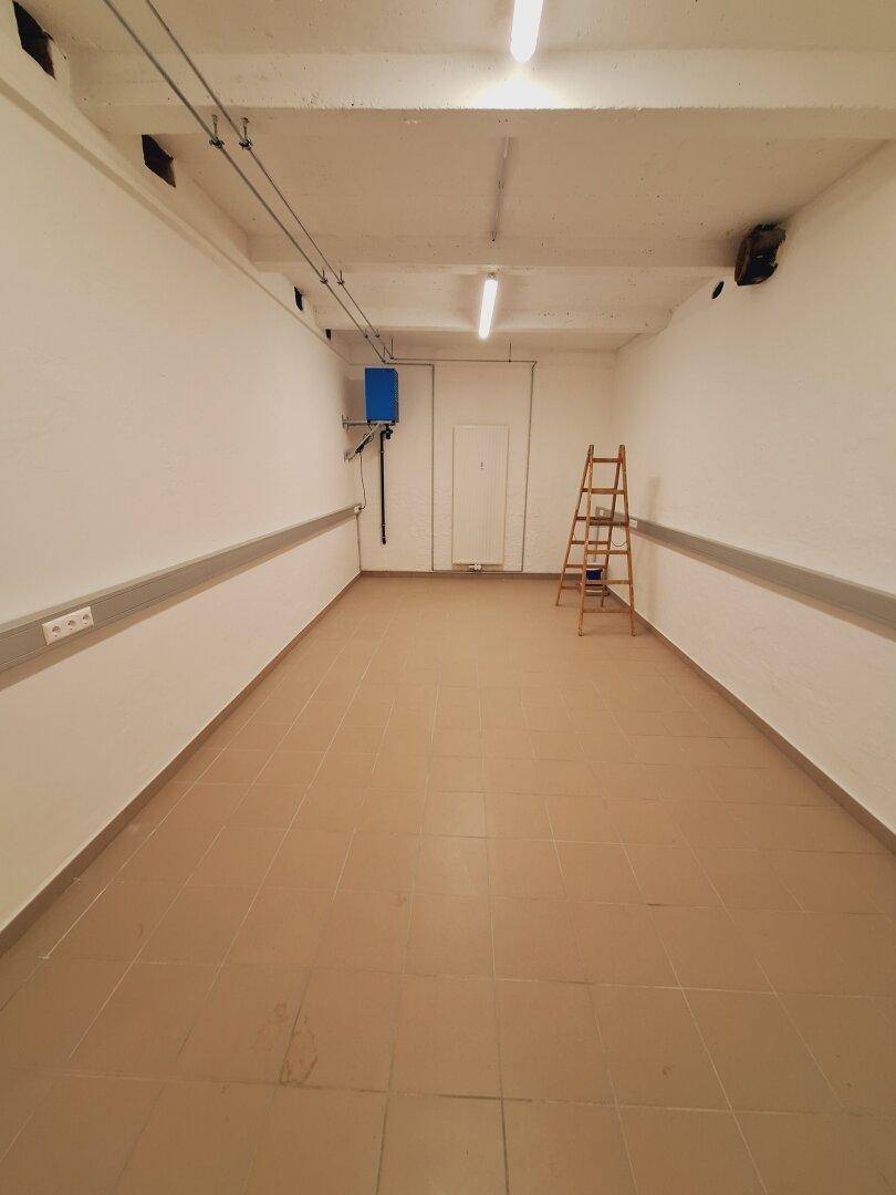 Geräumiger Kellerraum mit Fliesenboden, weiß gestrichenen Wänden und einfacher Deckenbeleuchtung.