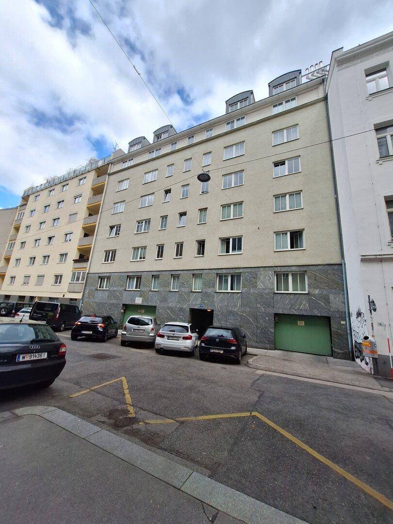 Mehrstöckiges Wohngebäude mit klassischer Fassade und Parkmöglichkeiten an der Straße.