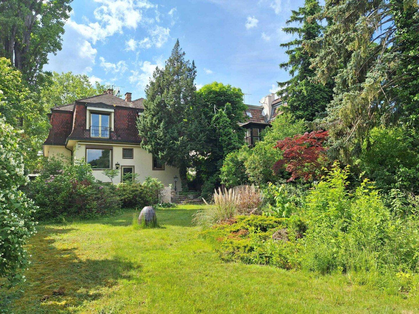 Idyllischer Gartenbereich hinter dem Haus mit weitläufiger Rasenfläche und vielfältiger Bepflanzung.