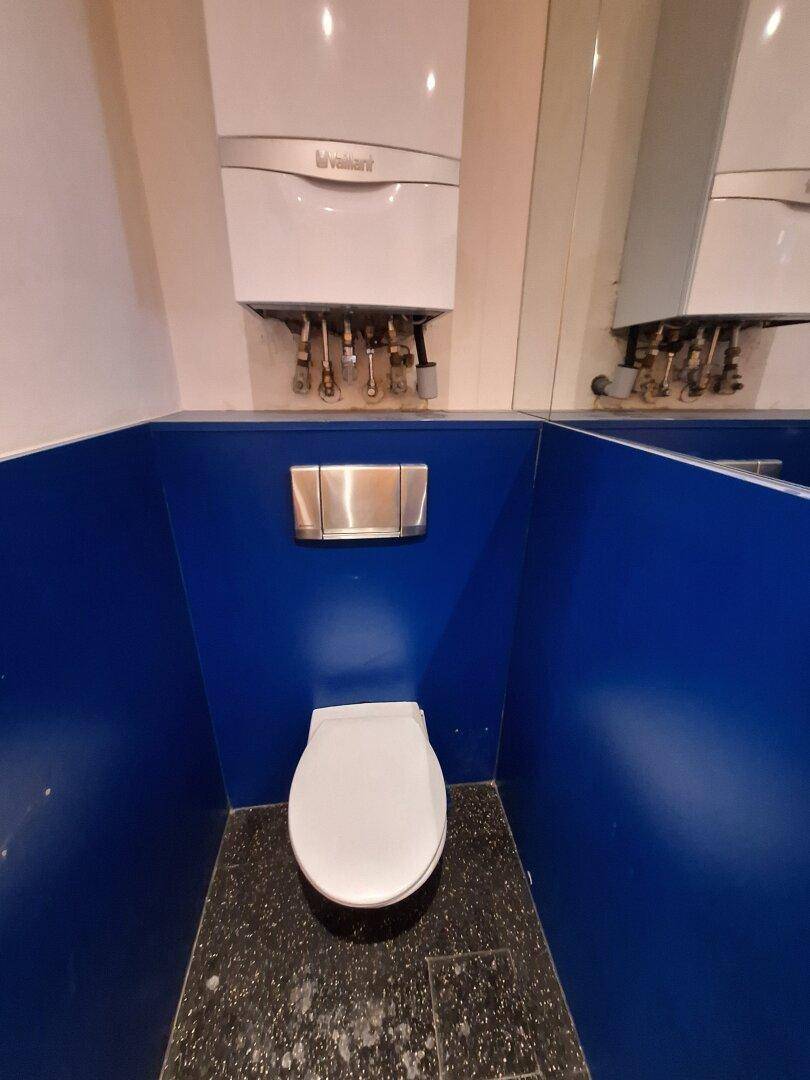 Kleine Gästetoilette mit blauen Wänden, wandhängendem WC und Gastherme.
