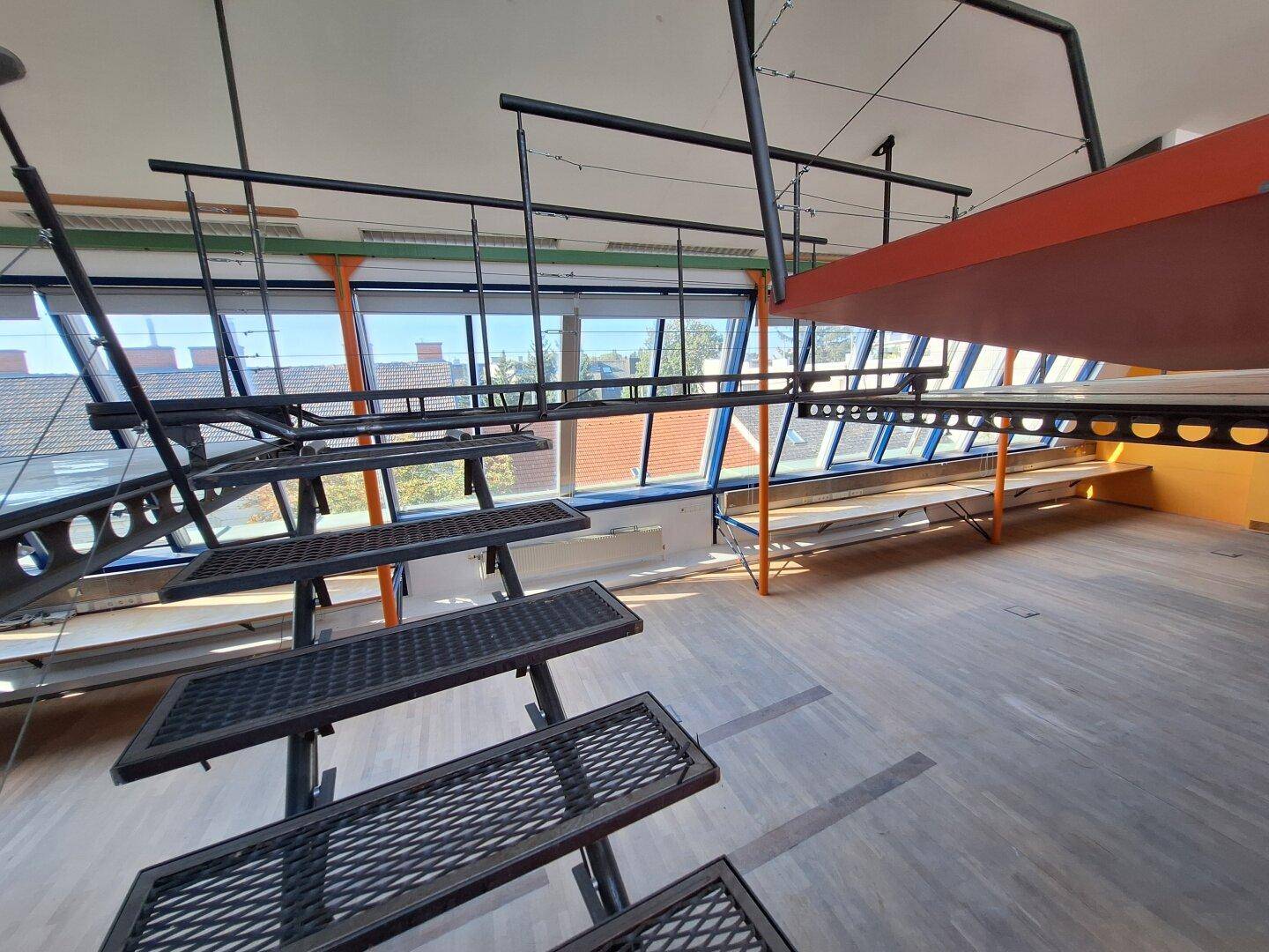 Blick von der Treppe auf die lange Fensterfront und die obere Empore in diesem modernen Loft.