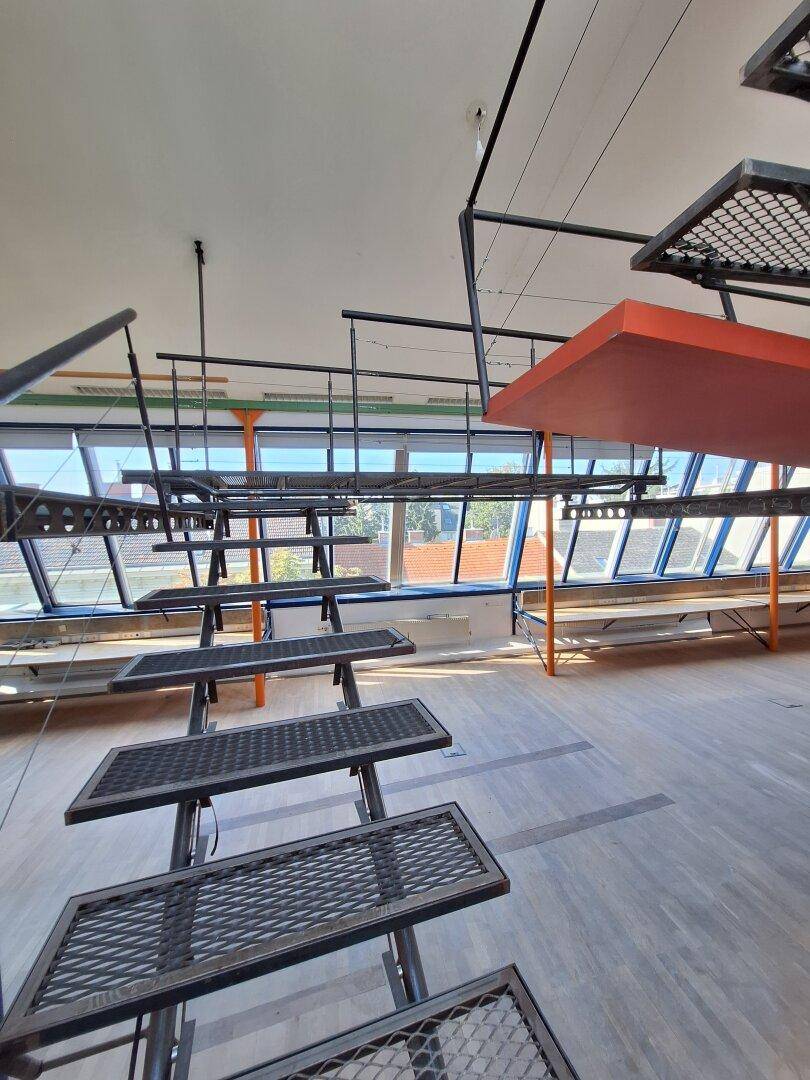 Perspektive von der Metalltreppe, die den Blick auf die weite Fensterfront und die Loftstruktur freigibt.