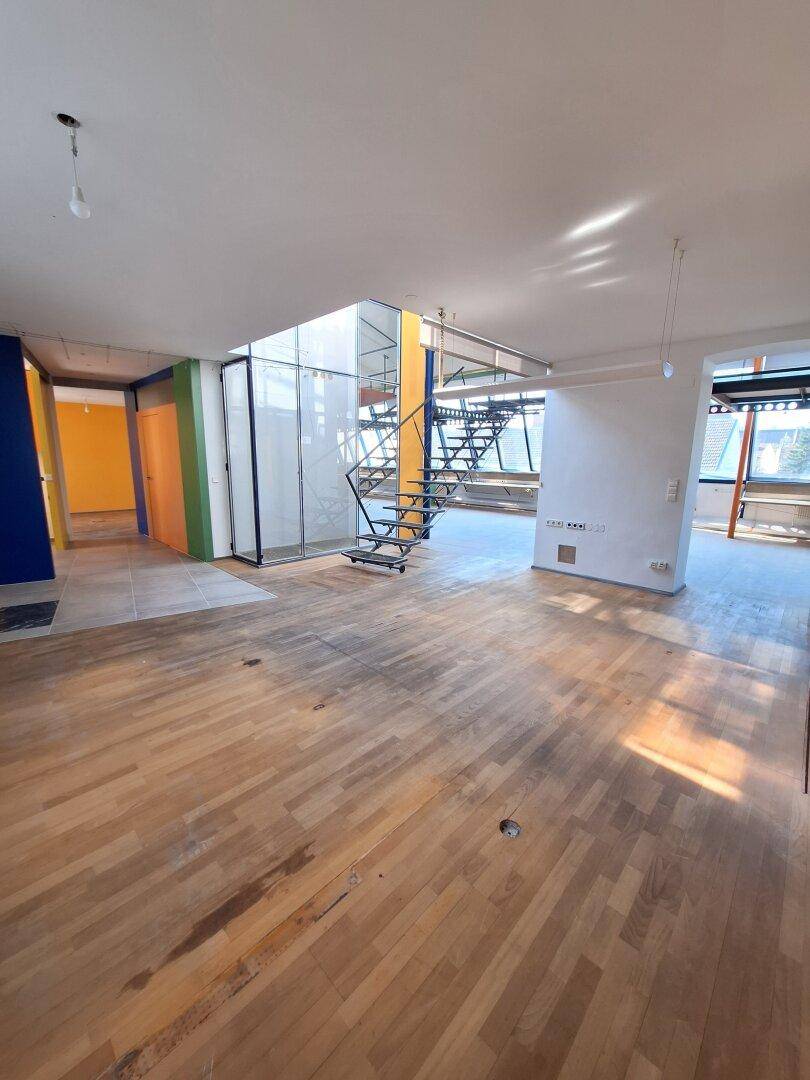 Heller Wohnbereich mit Holzboden und viel Tageslicht, der eine offene und moderne Atmosphäre schafft.