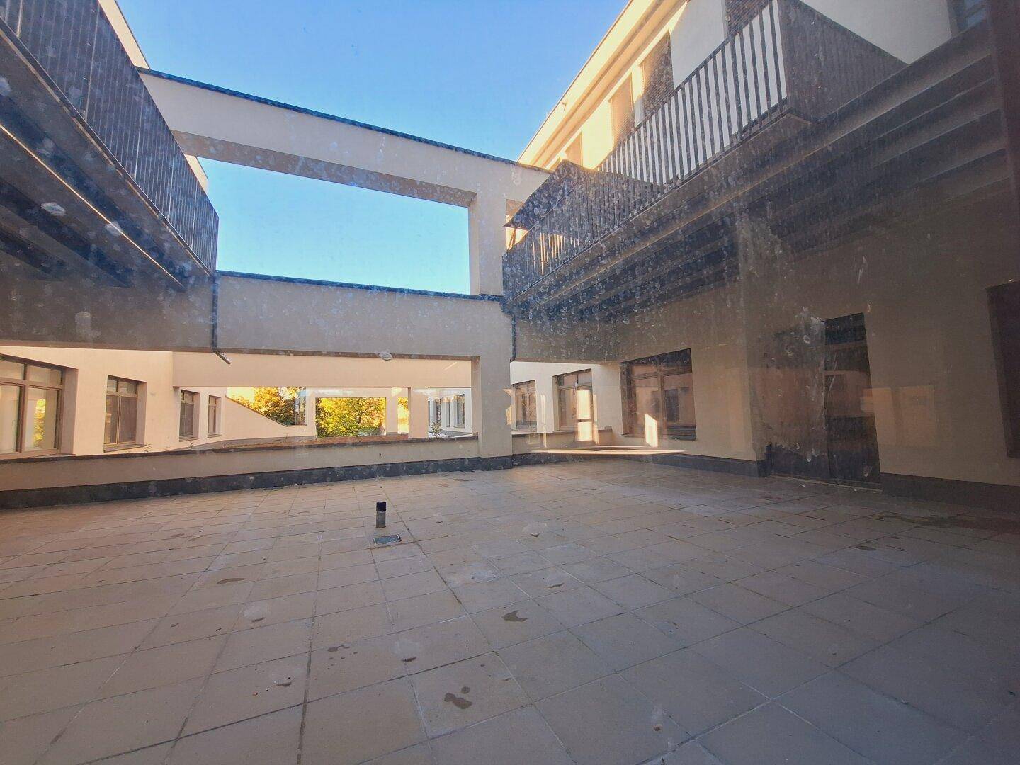 Große, geflieste Außenterrasse mit Blick auf die umliegenden Gebäude und Bäume.