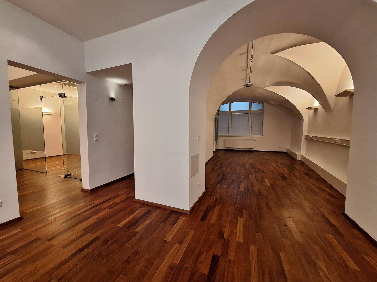 Großer Büroraum mit beeindruckenden Gewölbedecken und großen Fenstern, die viel Tageslicht hereinlassen.