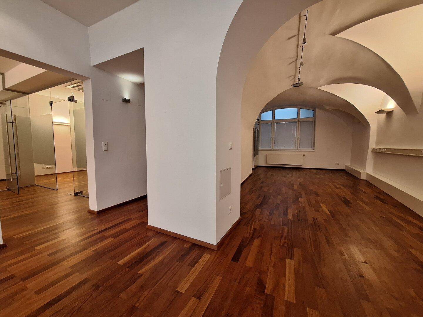 Großer Büroraum mit beeindruckenden Gewölbedecken und großen Fenstern, die viel Tageslicht hereinlassen.